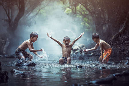 Happy boys has fun playing in the creek, Thailand countrysideの写真素材