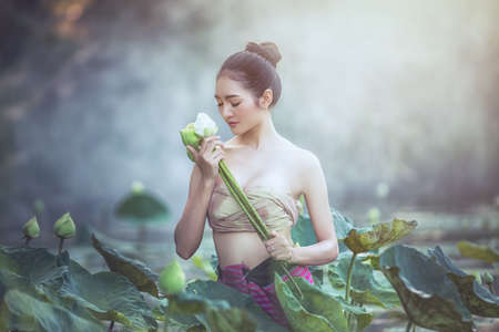 Asian woman harvest lotus flower in the garden, Thailand.の写真素材