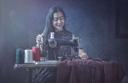 Woman using vintage sewing machine. adorable elderly woman sewing clothesの写真素材