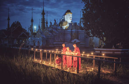 Young novice monks lighting up candlelight at temple, low light setting, Shan state, Myanmar.