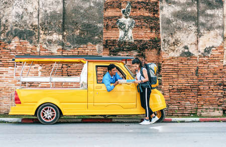 Asian woman travelers ask Tuk-Tuk driver about right direction on the map while exploring travel. At Ayutthaya historical park Thailand.の写真素材