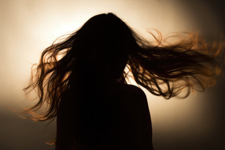 Silhouette of woman's head with waving hair, back light.の素材