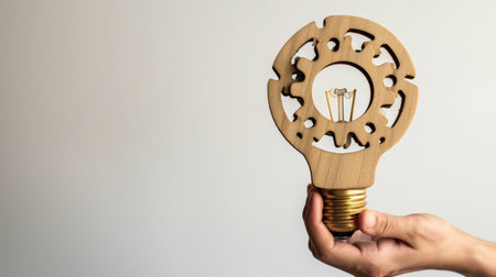 Business process and workflow automation with flowchart. Hand-holding wooden cog flowing process management lightbulb shape on white backgroundの素材