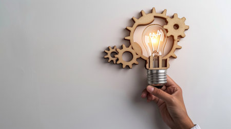 Business process and workflow automation with flowchart. Hand-holding wooden cog flowing process management lightbulb shape on white backgroundの素材