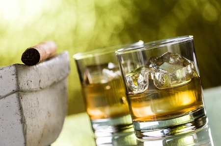 Two glasses of wiskey with ice cubes and a cigarの写真素材