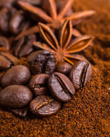Close-up of coffee beans on pile of roasted coffee. Coffee beans close-up on a background of ground coffee, cinnamon and spices.の写真素材