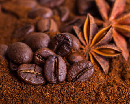 Close-up of coffee beans on pile of roasted coffee. Coffee beans close-up on a background of ground coffee, cinnamon and spices. Arabic roasting coffee - hot drink ingredient.の写真素材
