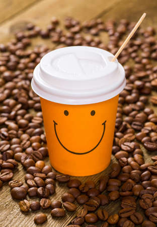 Paper cup of coffee latte and coffee beans on wooden tableの写真素材