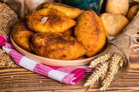 Traditional homemade pies with cabbage and sauerkraut on a plate. Freed Russian pastry pies on a wooden backgroundの写真素材