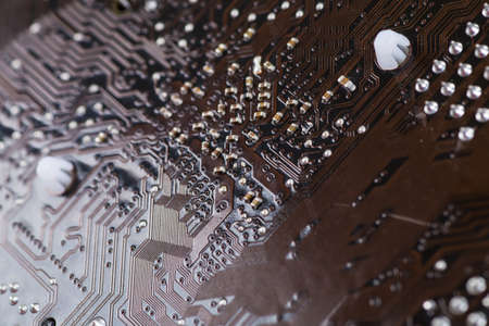 Macro closeup of a computer PCB using brown and black colors with silver soldered terminalsの写真素材
