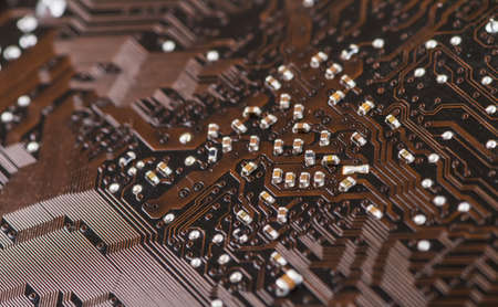 Macro closeup of a computer PCB using brown and black colors with silver soldered terminalsの写真素材