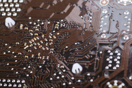 Macro closeup of a computer PCB   using brown and black colors with silver soldered terminalsの写真素材