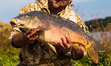 Happy angler with carp fishing trophy