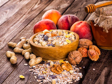 oatmeal in a sac, dried apricots, raisins, grapes, nuts on the background of wooden planks and sackingの写真素材