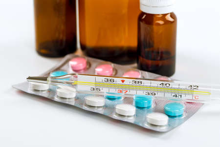 Various cold prescription bottles and a syringe isolated on a white background.