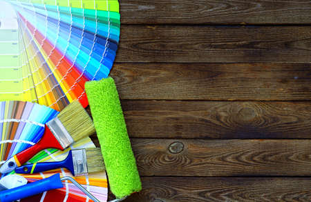 Painter and decorator work table with house project, color swatches, painting roller and paint brushesの写真素材