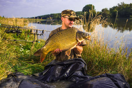 Happy angler with carp fishing trophy.Fish trophyの写真素材