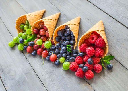 Berries. Raspberries, blackberries, blueberries in waffle cones on a wodden background. Healthy food conceptの写真素材
