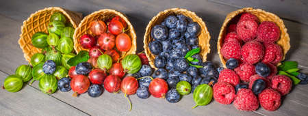 Berries. Raspberries, blackberries, blueberries in waffle cones on a wodden background. Healthy food conceptの写真素材