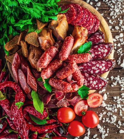 Food tray with delicious salami, pieces of sliced ham, sausage, tomatoes, salad and vegetable.の写真素材