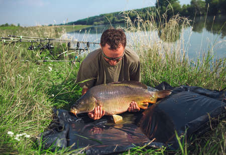 Happy angler with carp fishing trophyの写真素材