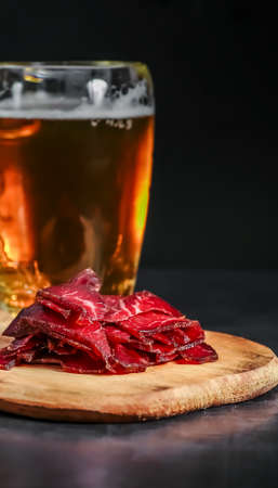 Pastterma is a delicacy of beef, sheep, pork and goat meat. Jerked meat, pastirma.thin sliced sausage jerked on a stone background and light beerの写真素材
