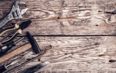 Hammer, screwdriver, wrench, tape measure, paint brush construction tools on wooden background with...