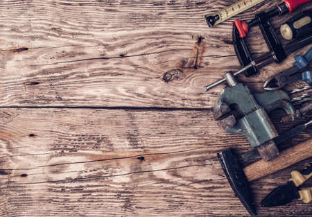 Hammer, screwdriver, wrench, tape measure, paint brush construction tools on wooden background with space for copyの写真素材