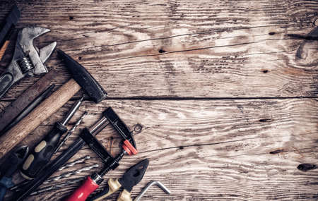 Hammer, screwdriver, wrench, tape measure, paint brush construction tools on wooden background with space for copyの写真素材