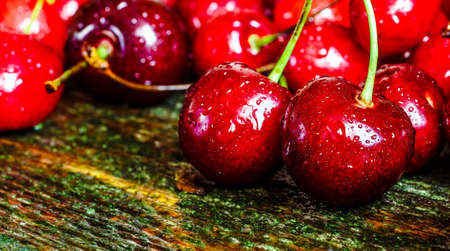Cherries on wooden table with water drops macro background