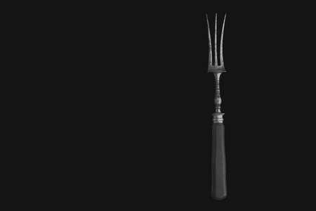 Metal vintage fork for meat steak on a black background.の写真素材