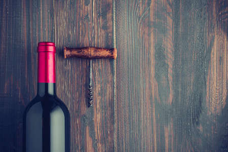 Wine bottle with corkscrew on wooden background