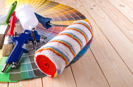 Painter and decorator work table with house project, color swatches, painting roller and paint...