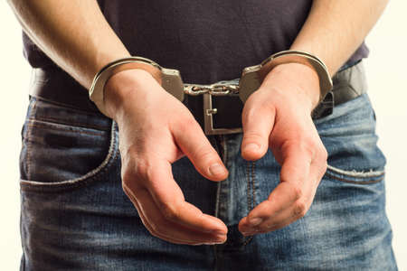 Adult male arrested and handcuffed.Man under Arrest. Hands with handcuffs in the front.Man with his...