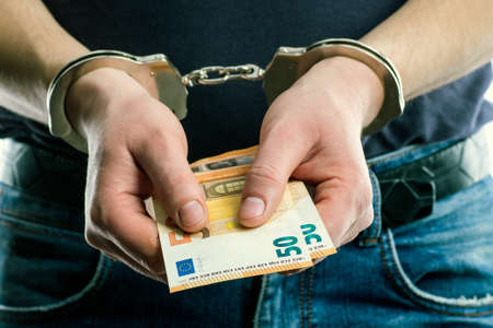 Adult male arrested and handcuffed.Man under Arrest. Hands with handcuffs in the front.Man with his hands handcuffed in criminal concept.の写真素材