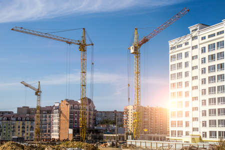 Construction site background. Hoisting cranes and new multi-storey buildings. I.ndustrial...
