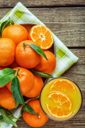 Ripe Mandarin fruit peeled open and place on old rustic look timber with group of mandarin fruits and leaves out of focus on the backgroundの写真素材