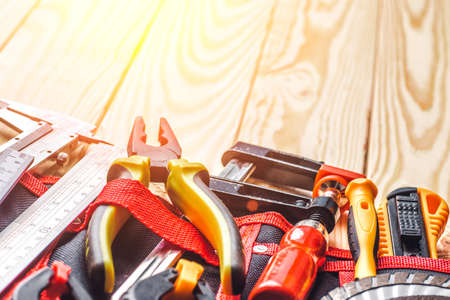 Tool belt with tooling construction level protective gloves on wooden board.Carpenter tools â A carpenters bench with various toolsの写真素材