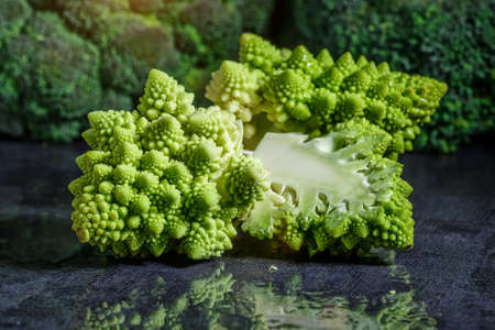 Macro photo green fresh vegetable ramonesco broccoli. Fresh green Romanesco Cauliflower on a black stone table.Vegetables for diet and healthy eating.Organic food.の写真素材