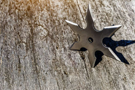 Shuriken (throwing star), traditional japanese ninja cold weapon stuck in wooden background,Silver shuriken with star shape.Samurai, throwing weaponsの写真素材