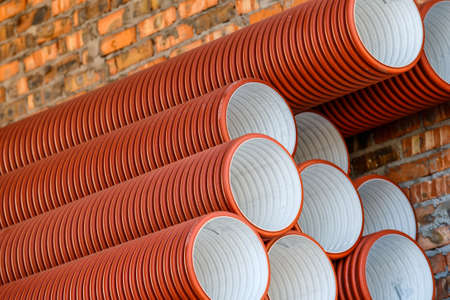 Warehouse of finished plastic pipes industrial outdoors storage site. orange PVC pipes stacked in...