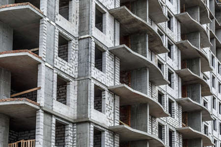 Extensive scaffolding providing platforms for work in progress on a new apartment block,Tall building under construction with scaffolds,Freestanding tower crane on a building siteの写真素材
