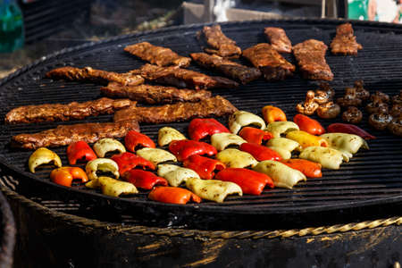 Fried vegetables in a metal stand at the fair. barbecue at the festival. Cheese and roasted veal on...