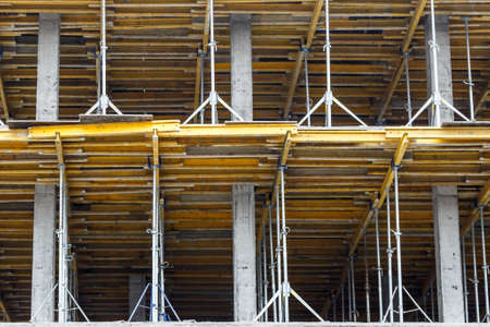 Extensive scaffolding providing platforms for work in progress on a new apartment block,Tall building under construction with scaffolds,Freestanding tower crane on a building siteの写真素材
