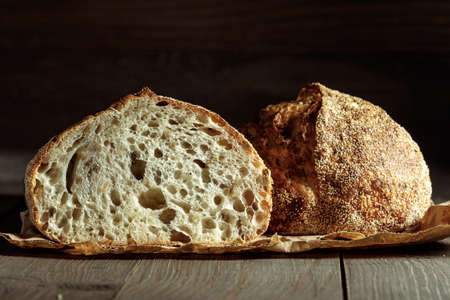 Bread, traditional sourdough bread cut into slices on a rustic wooden background. Concept of traditional leavened bread baking methods. Healthy food.の写真素材