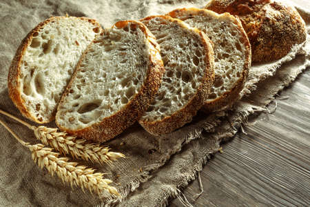 Bread, traditional sourdough bread cut into slices on a rustic wooden background. Concept of traditional leavened bread baking methods. Healthy food.の写真素材
