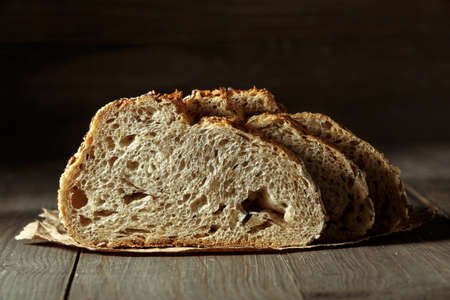 Bread, traditional sourdough bread cut into slices on a rustic wooden background. Concept of...