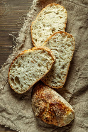 Bread, traditional sourdough bread cut into slices on a rustic wooden background. Concept of...