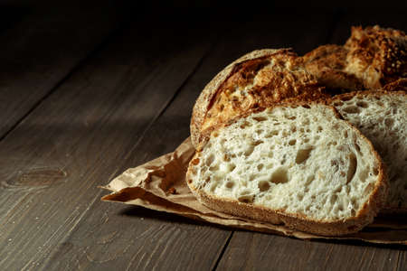 Bread, traditional sourdough bread cut into slices on a rustic wooden background. Concept of...