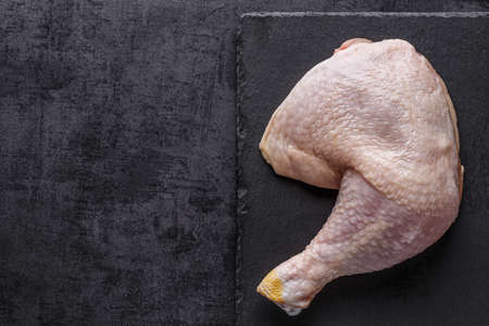 Shooting for the catalog. Raw chicken legs with spices and vegetables on a wooden cutting board. Black background. Top viewの写真素材